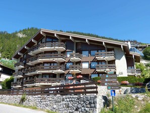 A multi-story hotel with balconies, a stone wall, and signs indicating amenities like a restaurant, bar, and pool.
