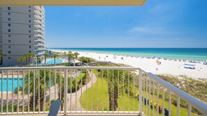 A balcony with a view of a beach, a pool, and a building with multiple floors. - Luxurious Beachfront Corner Unit at Seaside Beach & Racquet 4407 (Orange Beach)