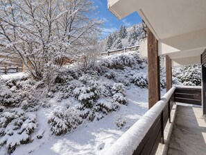 A snow-covered landscape with a wooden deck and a building with a balcony.