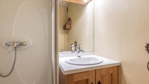 Een badkamer met een douche, wastafel en spiegel.