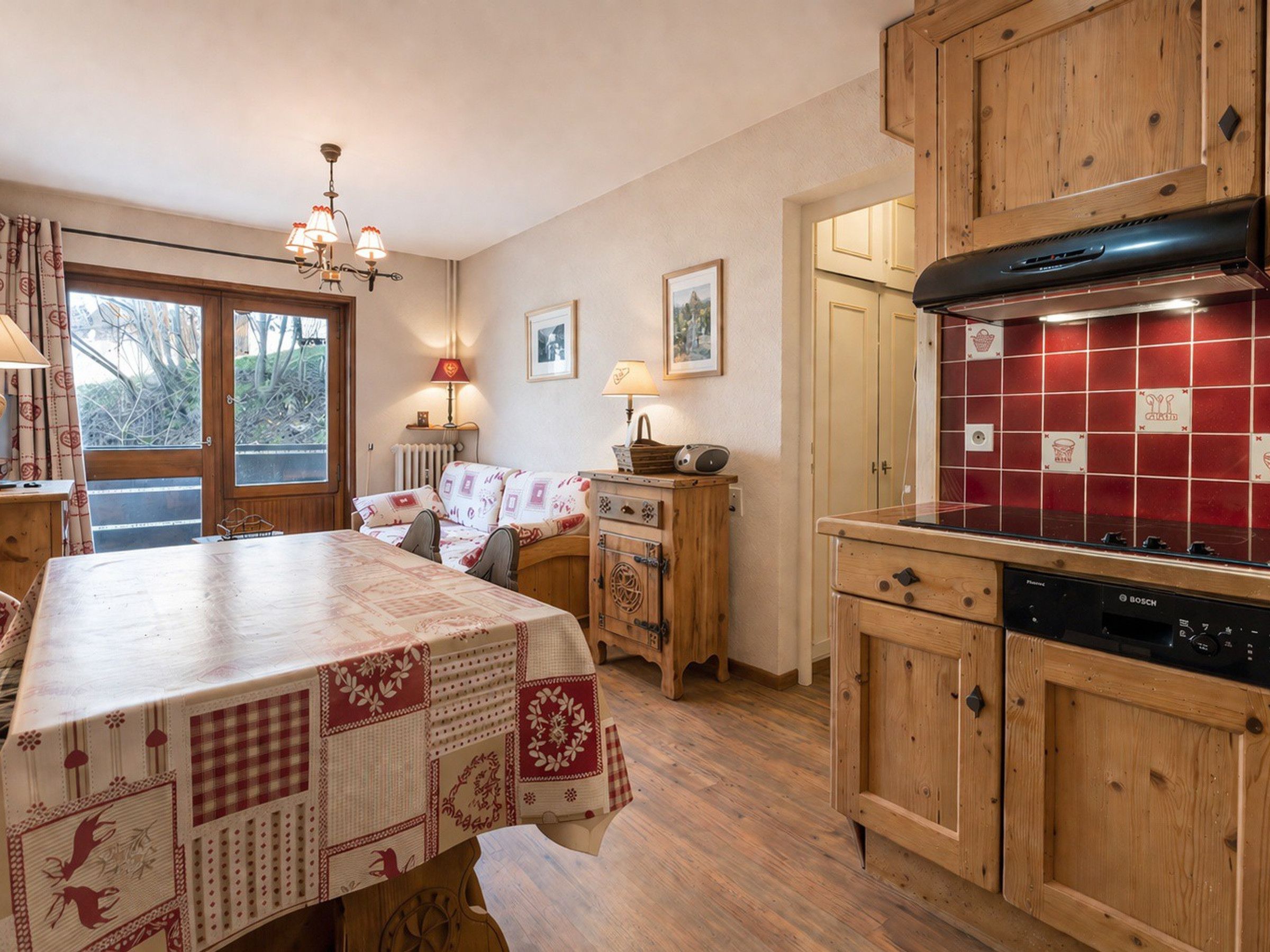 Una cocina acogedora con armarios de madera, lavavajillas Bosch y salpicadero con azulejos rojos.