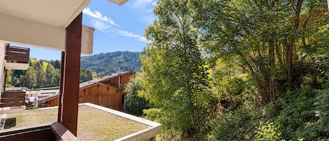 Una terraza de madera con vistas a una montaña y un bosque.