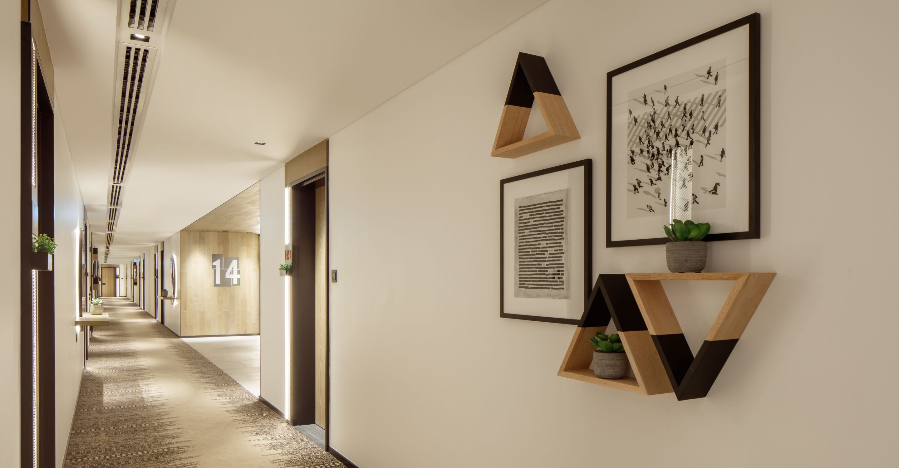 A hallway with framed artwork, a plant, and a geometric shelf.