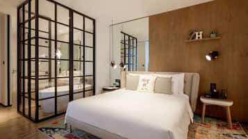 Un dormitorio moderno con una cama grande, un separador de vidrio, una pared de madera, un estante pequeño y una mesita de noche.