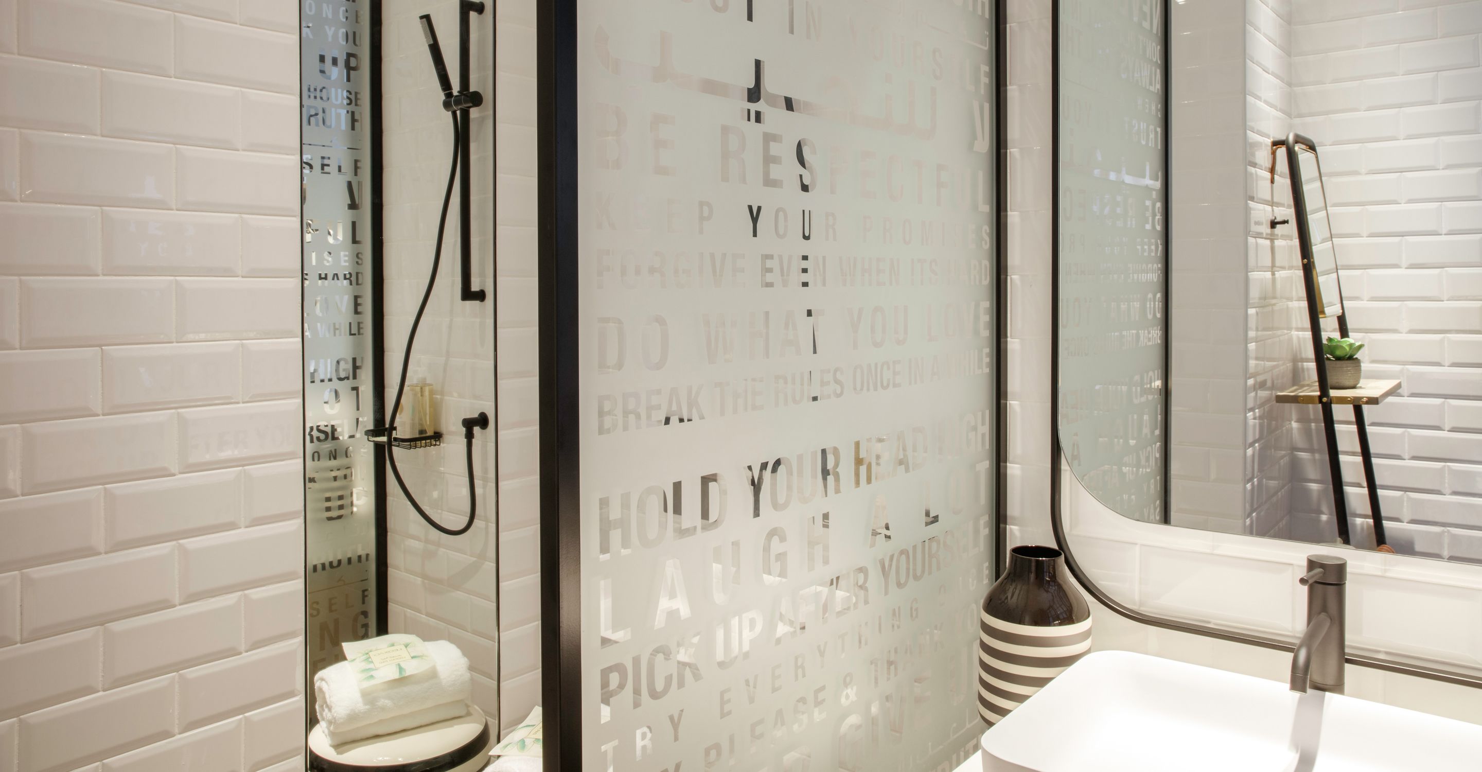 Un baño moderno con cabina de ducha de vidrio, un lavabo blanco y un espejo.