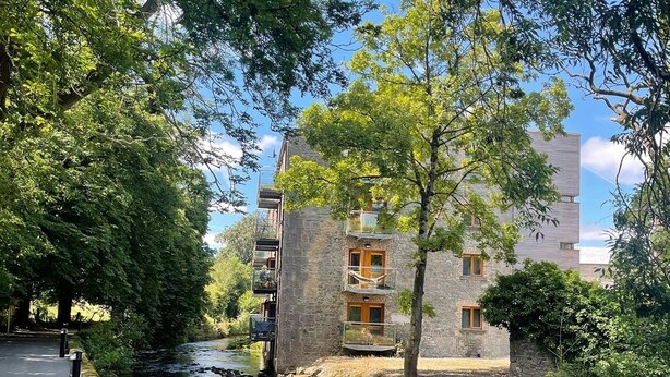 A riverside building with stone walls, a balcony, and a pathway alongside the water. - Elegant  townhouse steps from historic Birr Castle Demense  (Birr)