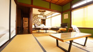 A traditional Japanese room with tatami flooring, a low table, and a bed with a futon. - Super Tomato House Takayama (Takayama)