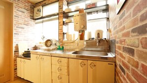 A kitchen with a brick wall, a sink, and a dish rack. - Super Tomato House Takayama (Takayama)