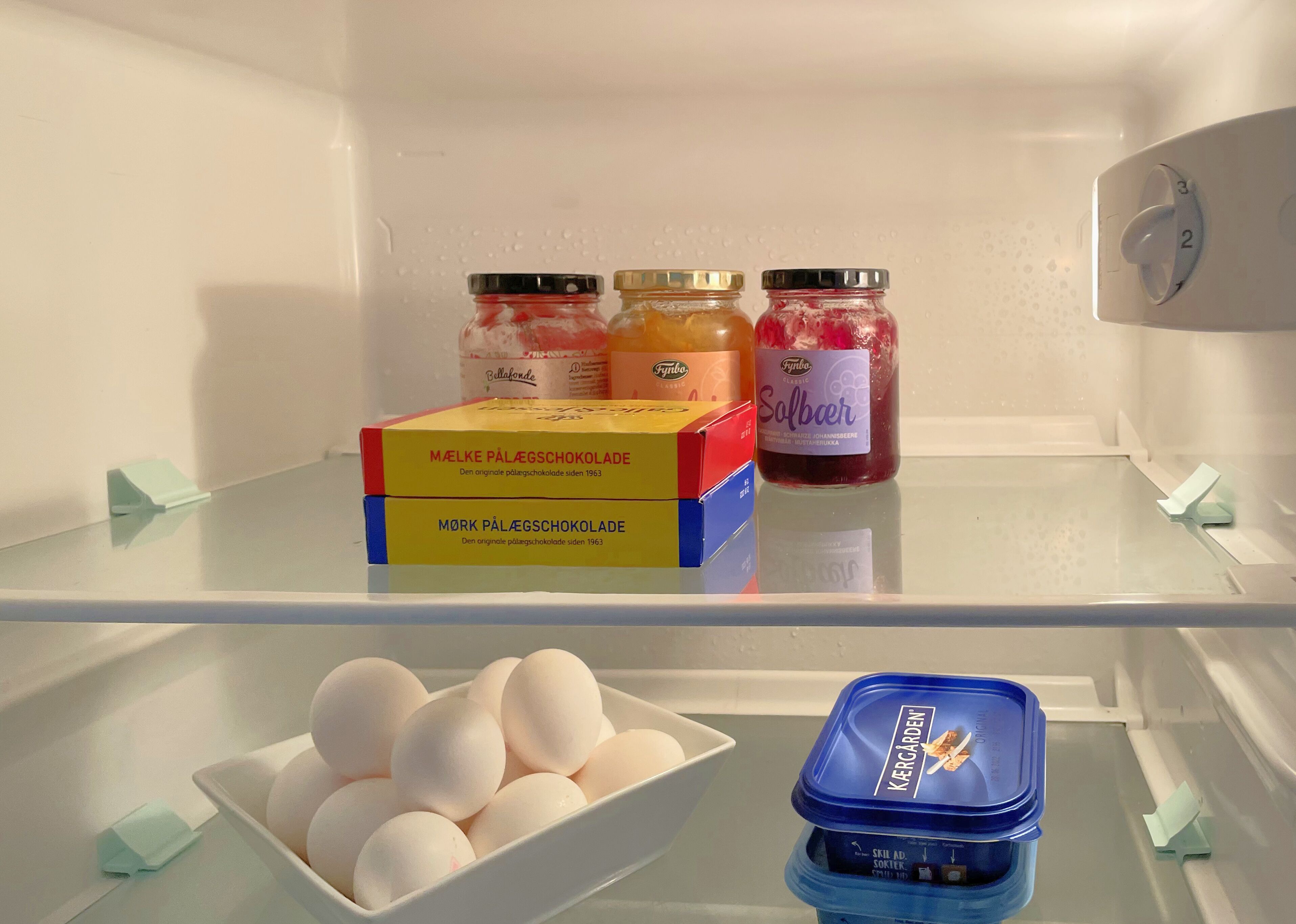 A refrigerator with two boxes of Mörk Pälägschokolade, two jars of Fynbo Classic, and a container of Kergarden.