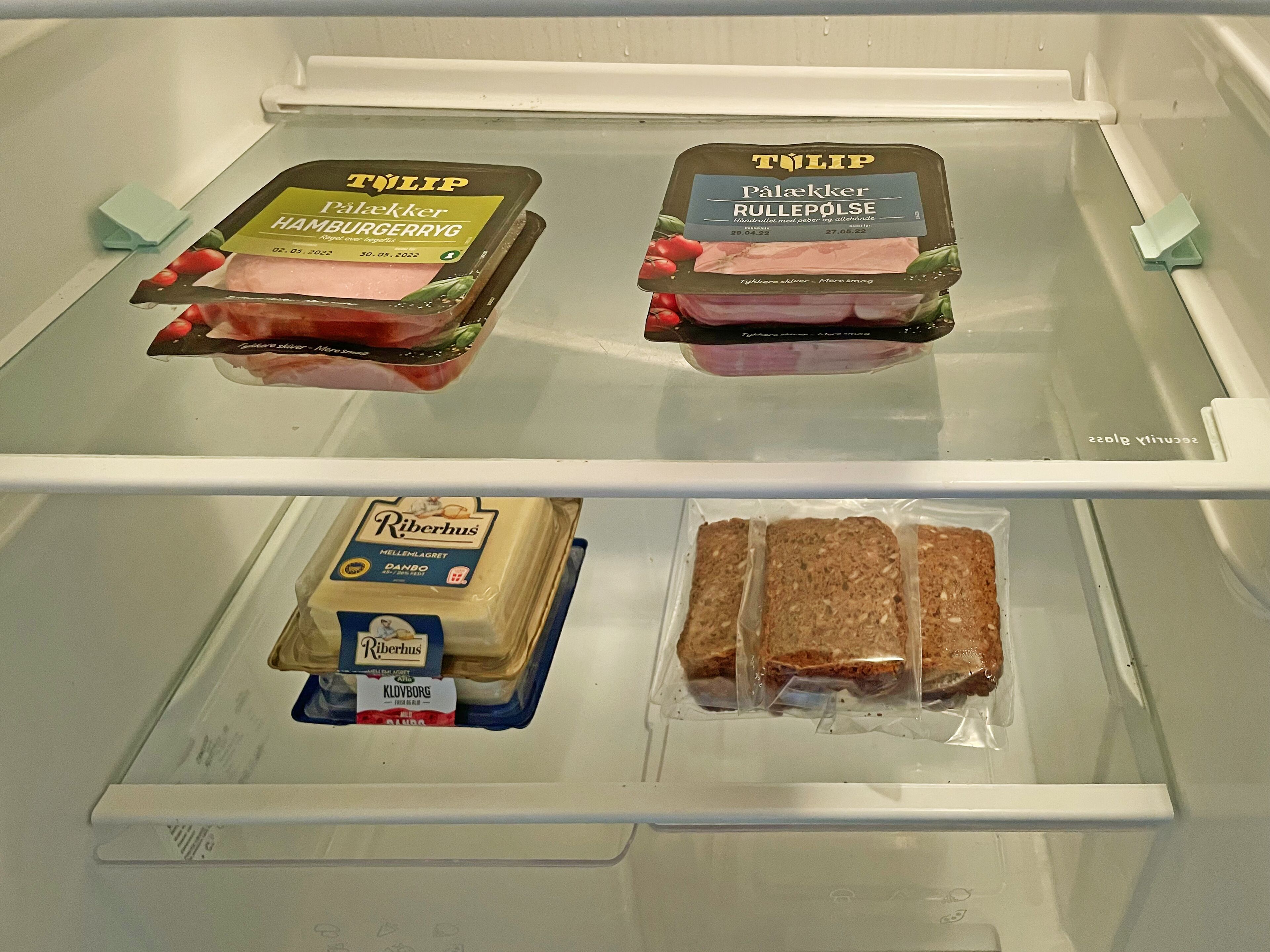 A refrigerator with two TÖLIP ham products and two packages of Riberhus bread.