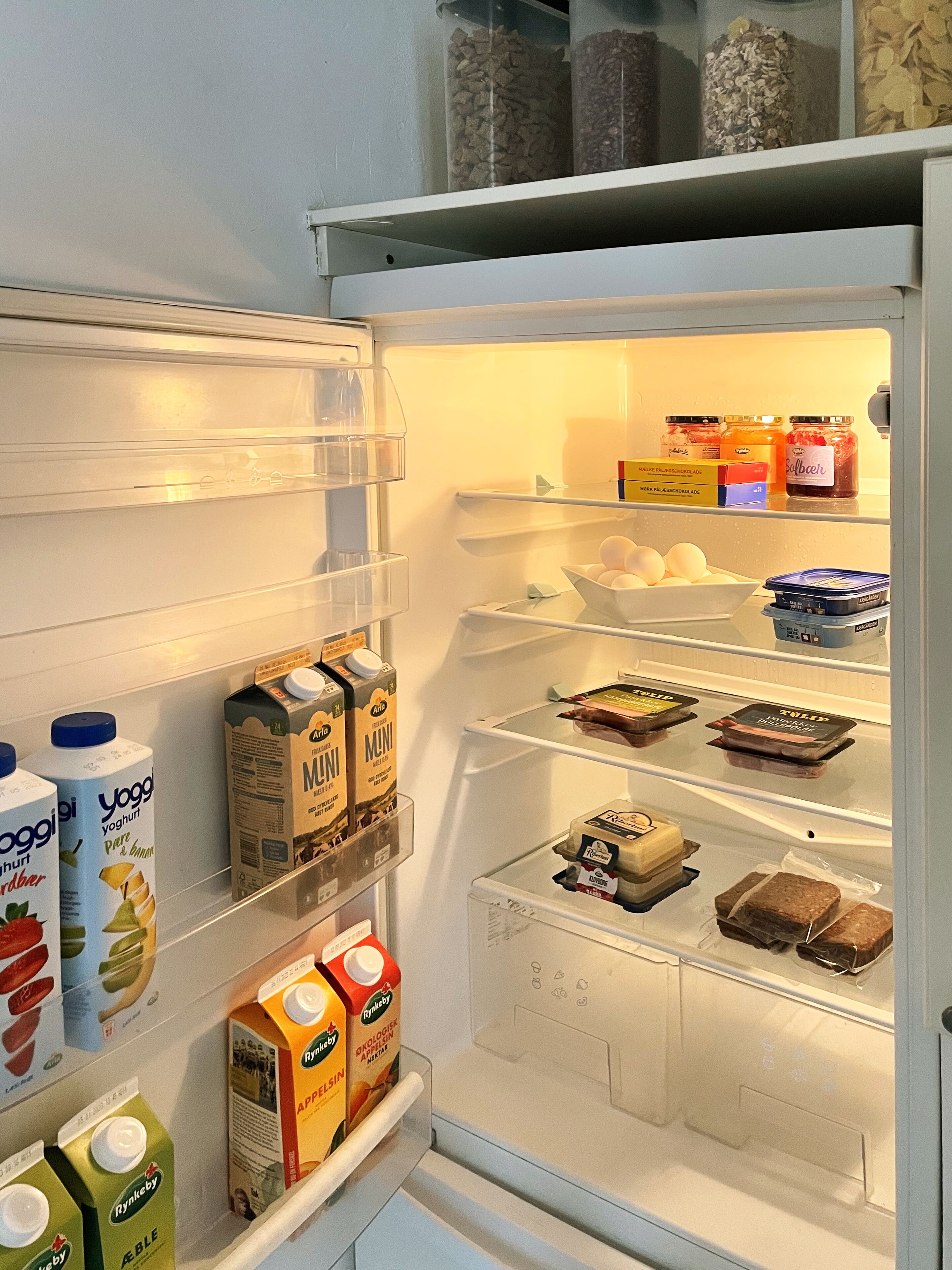 Un refrigerador lleno de diversos alimentos, incluyendo lácteos, huevos y productos envasados.