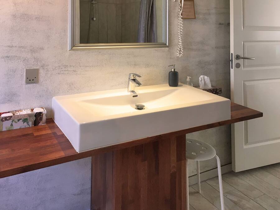 Un baño con lavamanos blanco, encimera de madera y un espejo encima.