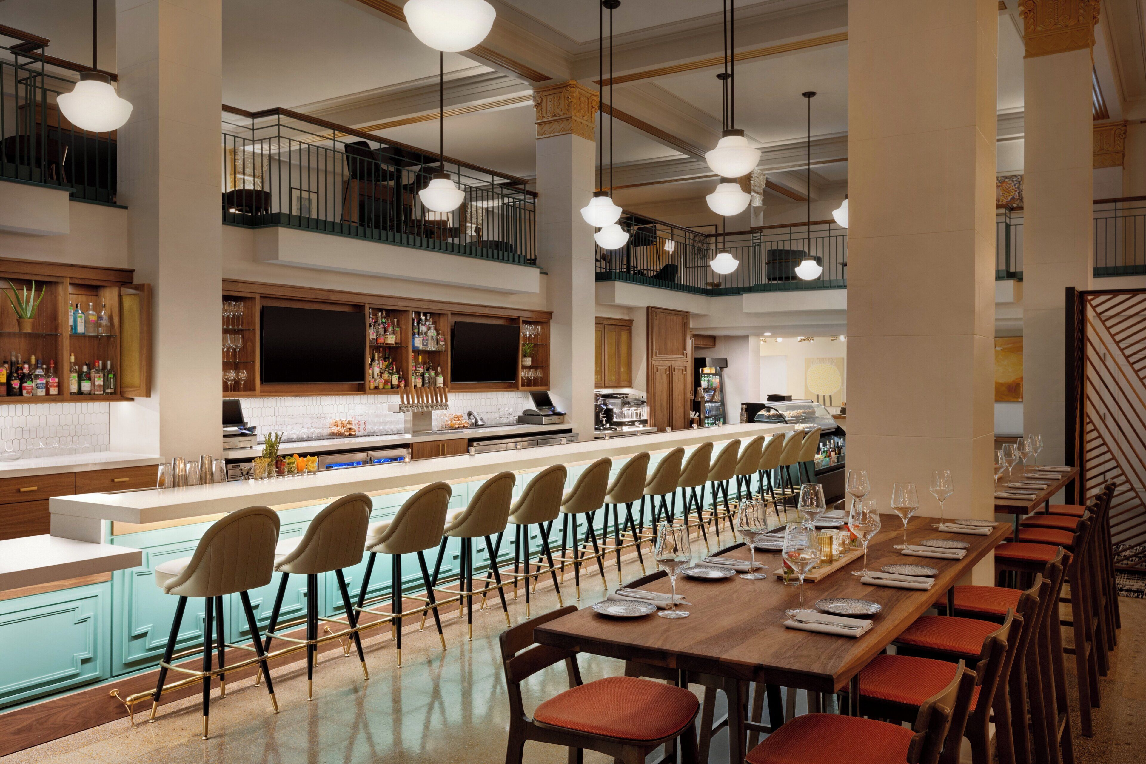 A spacious bar area with a long counter, multiple seating options, and a staircase leading to an upper level.