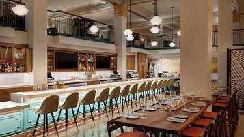 A spacious bar area with a long counter, multiple seating options, and a staircase leading to an upper level.