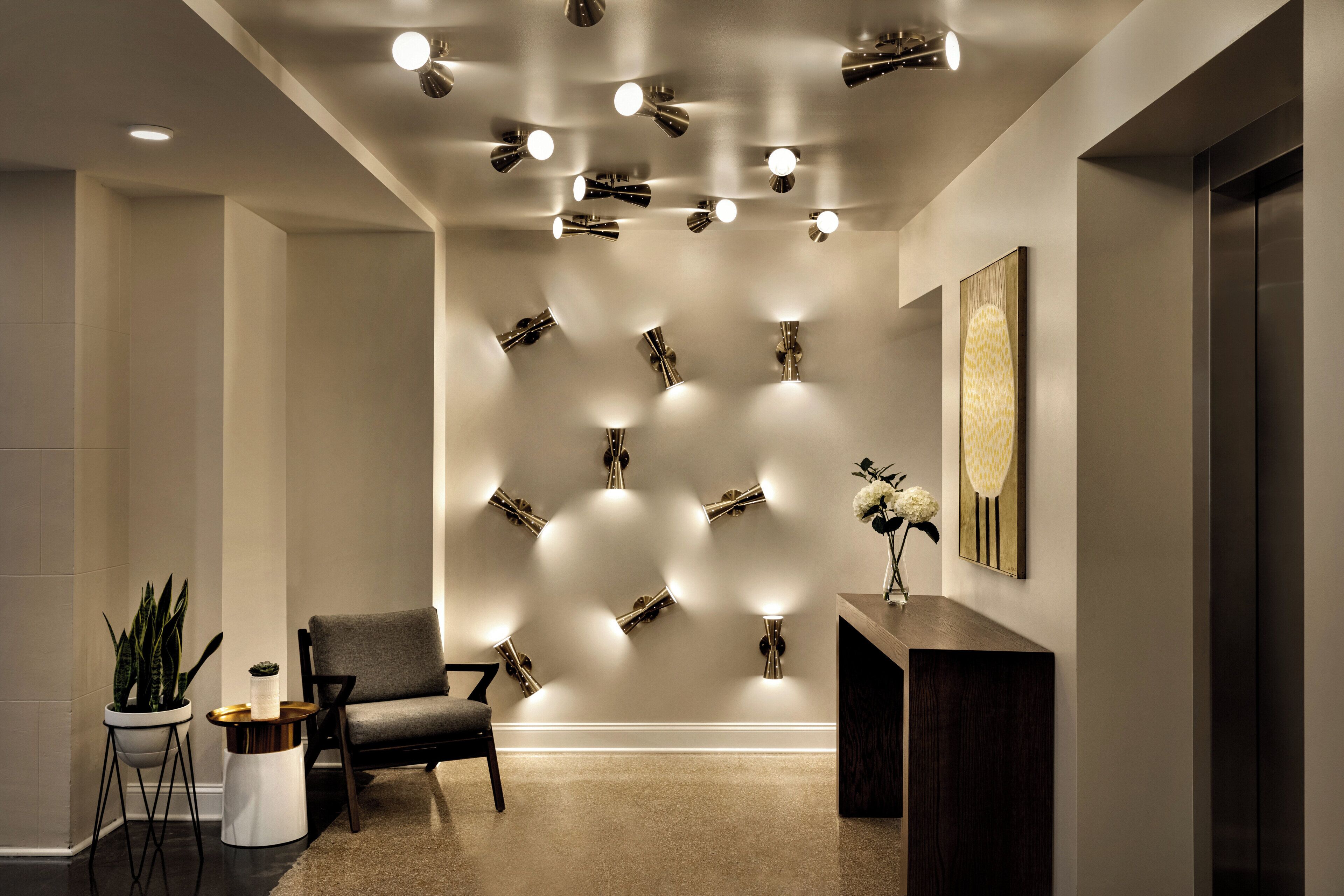 Ein modernes Interieur mit einer Sitzecke, einer Wandleuchte und einem Wandbild.
