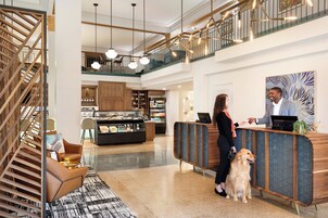 Un hall de hotel con mostrador de recepción, una escalera y una zona de estar con alfombra estampada.