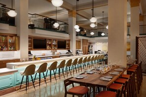 Tilava ravintola, jossa on pitkä palvelutiski, useita ruokapöytiä ja monipuoliset istumapaikkavaihtoehdot.
