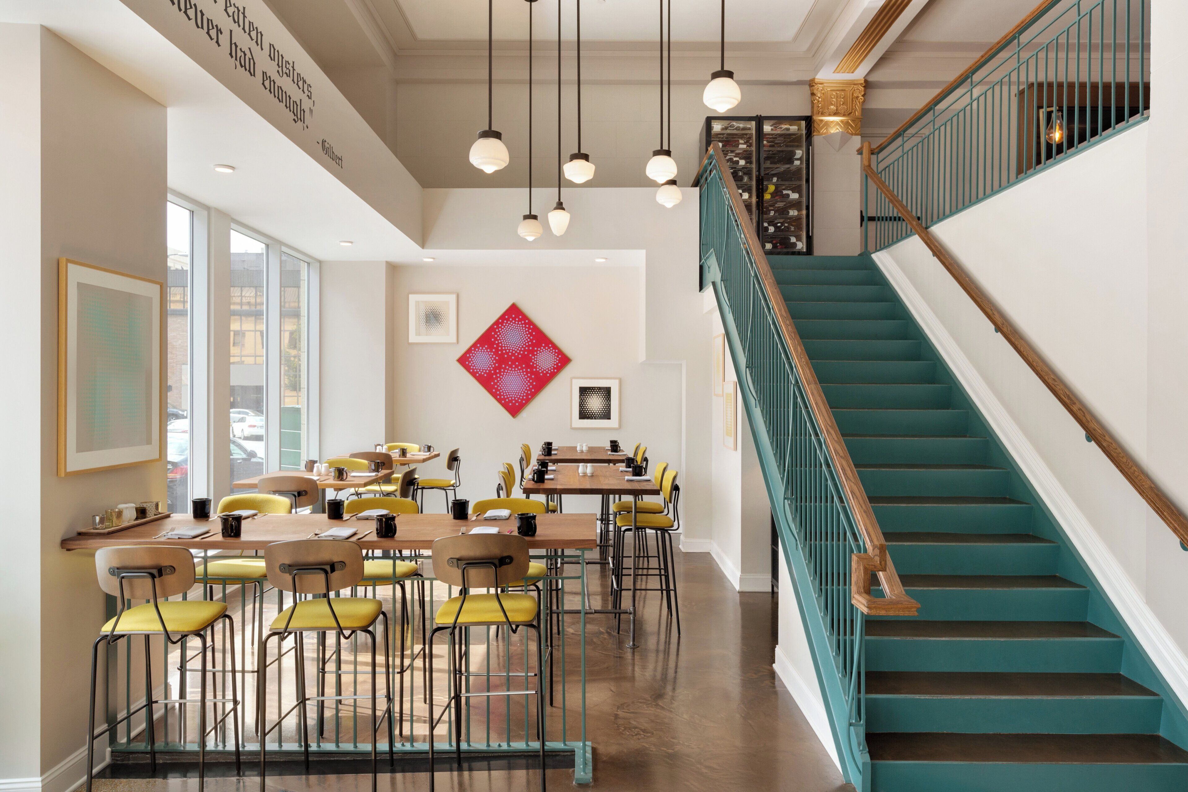 Un interior moderno con una escalera, comedor y obras de arte.