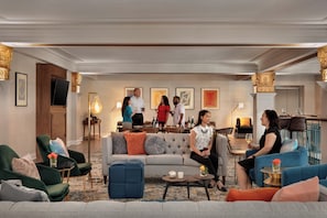 A spacious lounge area with multiple seating options, a central coffee table, and a bar area in the background.