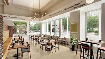 A spacious cafe with multiple tables and chairs, large windows offering a view of the street, and decorative quotes on the walls.