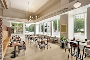 A spacious cafe with multiple tables and chairs, large windows offering a view of the street, and decorative quotes on the walls.