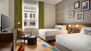 A hotel room with a bed, a desk with a TV, a chair, a small table, and a window with curtains. - Hotel Indigo Winston-Salem Downtown by IHG (Winston-Salem)
