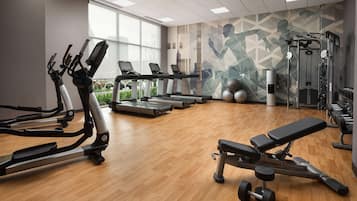 A gym with treadmills, elliptical machines, a bench, and free weights.
