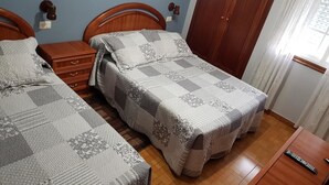 A bedroom with two single beds, wooden headboards, a wooden wardrobe, a bedside table with a lamp, and a window with curtains. - Rincón Do Demo (Nigran)