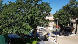 A parking area with a handicapped parking sign, trees, and a building with a sign that reads "Hotel de Commerce". - Rincón Do Demo (Nigran)