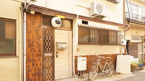 A building with a tiled entrance, a bicycle parked outside, and an air conditioning unit on the wall. - Tomato House Takayama (Takayama)