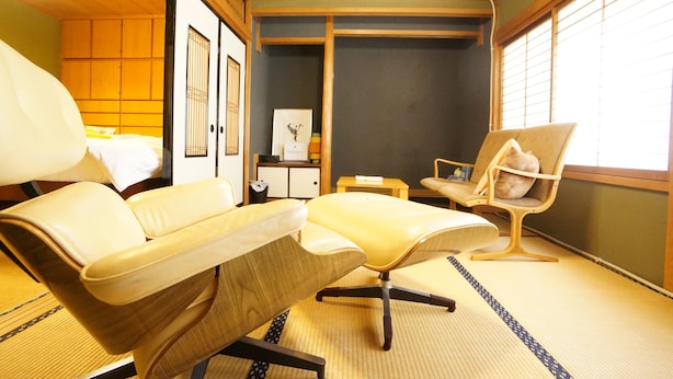 A traditional Japanese room with tatami flooring, a low wooden bed, a sofa, a chair, and a small table. - Tomato House Takayama (Takayama)