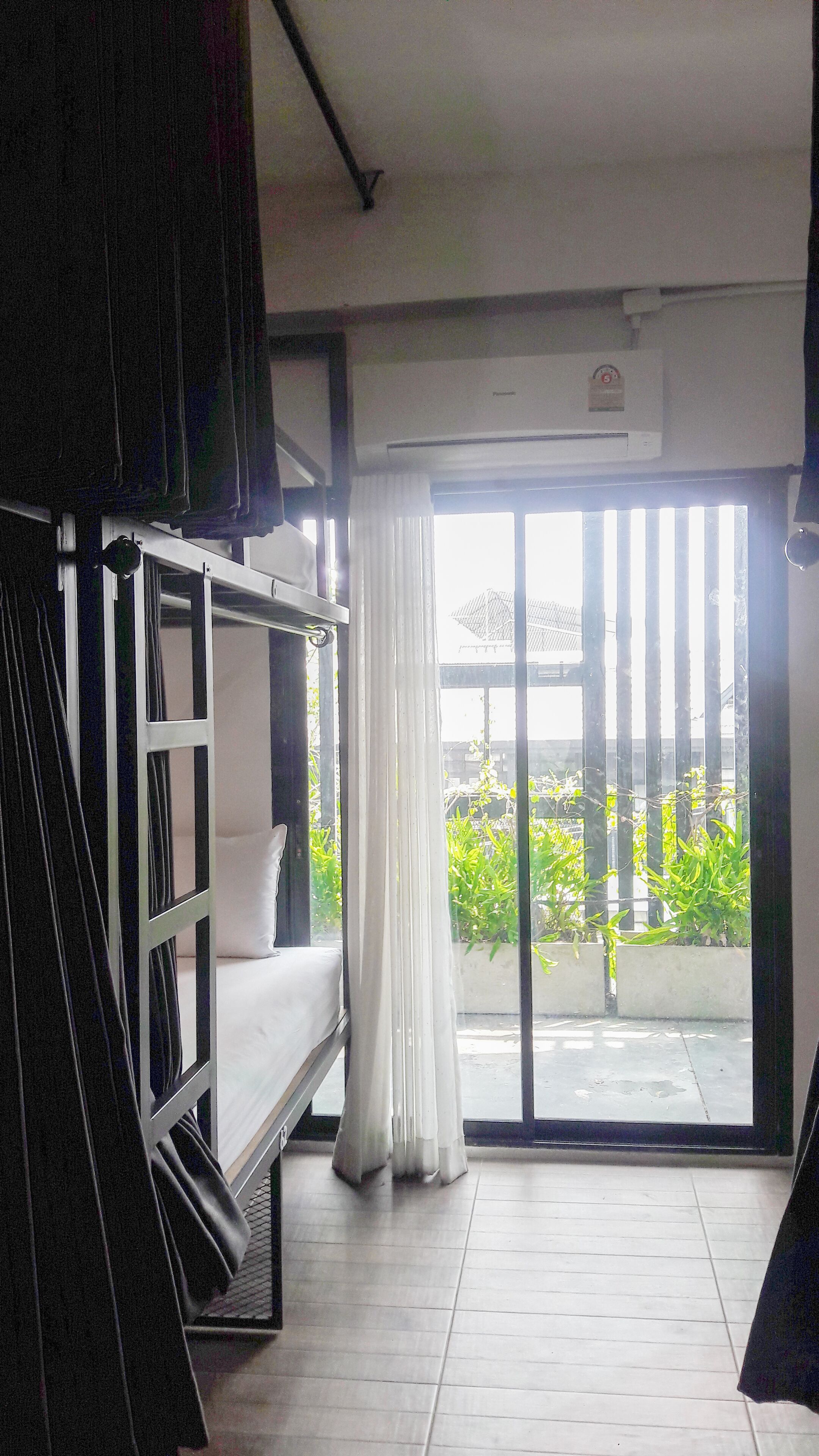 Una habitación con literas, una puerta corrediza al balcón y un ventilador de techo.
