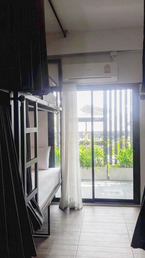A room with a bunk bed, a sliding glass door to a balcony, and a ceiling fan. - Hobnob Hostel - Adults Only (Chiang Mai)