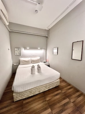 A neatly made bed in a hotel room with a headboard, a bedside table with a lamp, and a wall-mounted mirror. - Hobnob Hostel - Adults Only (Chiang Mai)