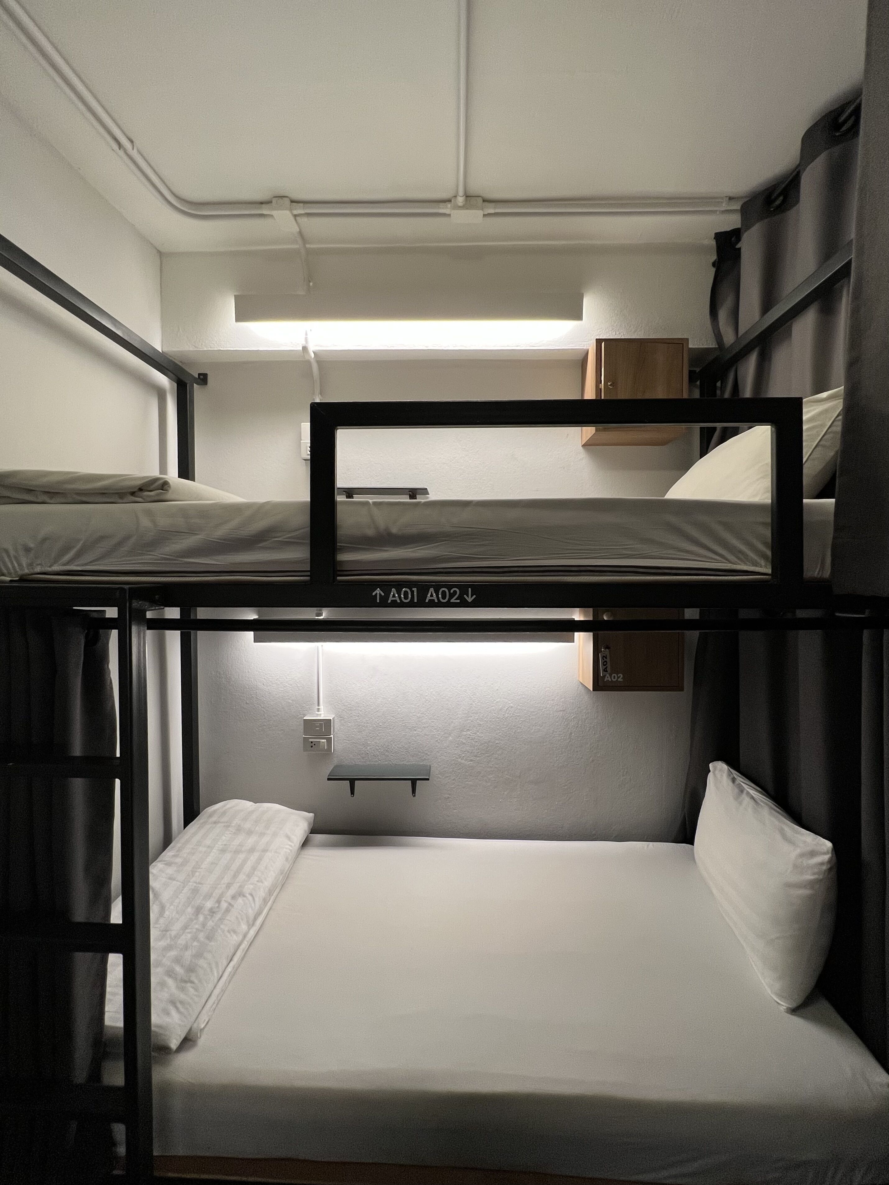 A bunk bed room with a headboard, a shelf, and a small table.