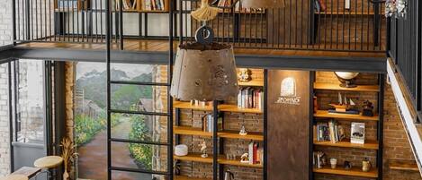 A spacious loft with a high ceiling, exposed brick walls, and a mezzanine level.