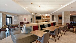 Un moderno vestíbulo de hotel con una zona de estar, un bar y una pantalla de televisión.