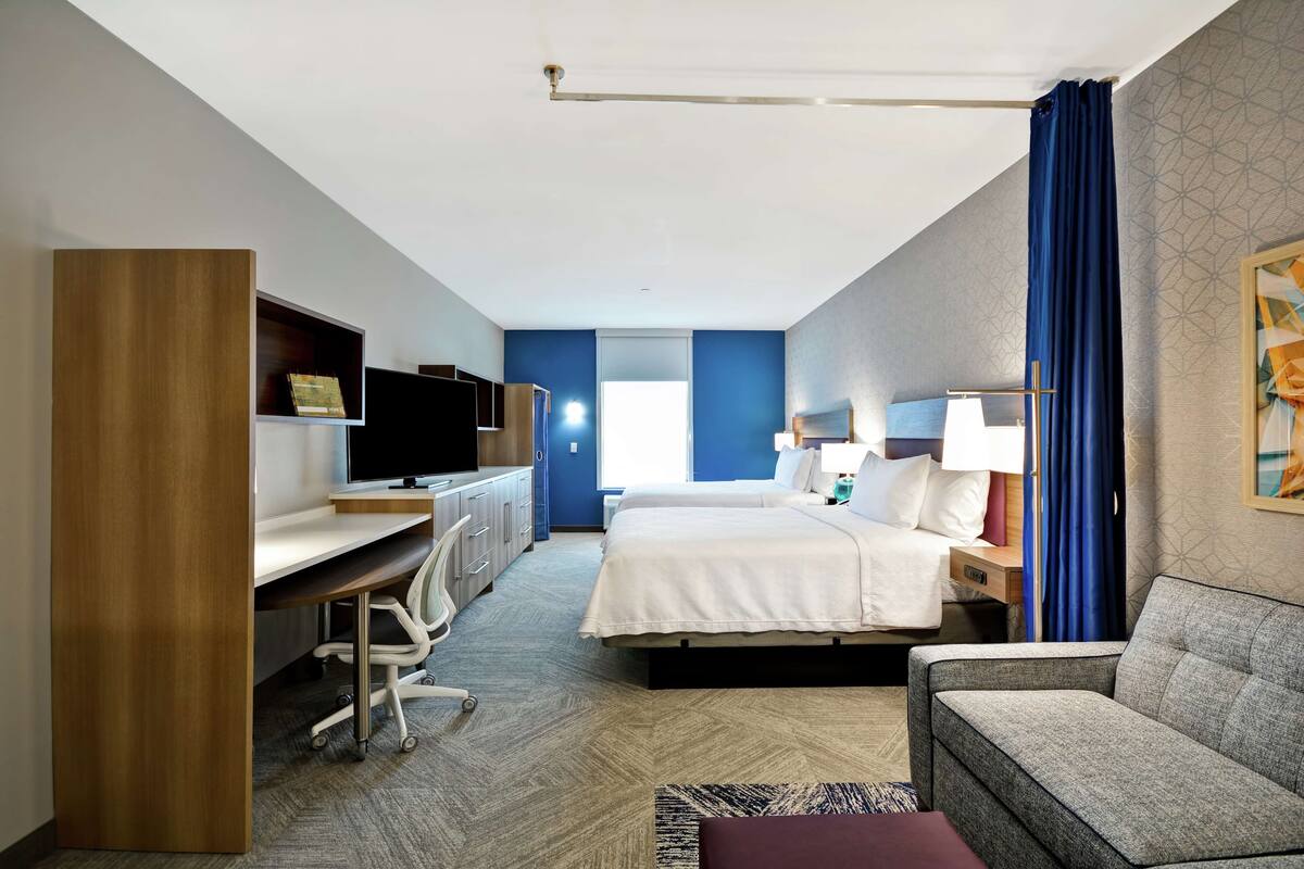 Une chambre d’hôtel avec un lit, un bureau avec un ordinateur, un canapé et une télévision.
