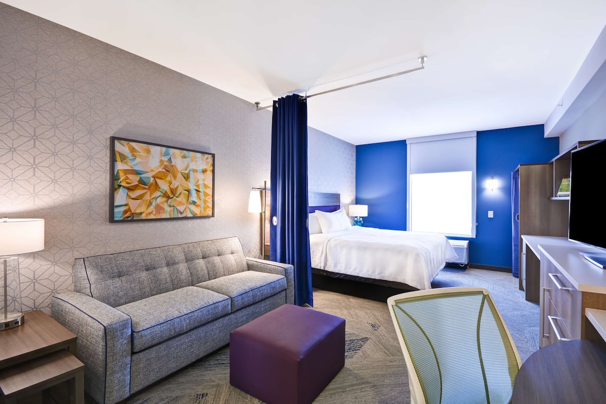 Une chambre d’hôtel avec un canapé, un lit, un bureau et une télévision.