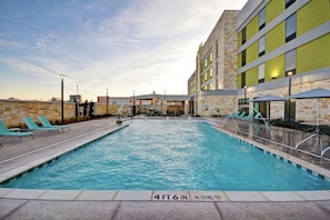 Relax by the pool surrounded by lounge chairs and umbrellas.