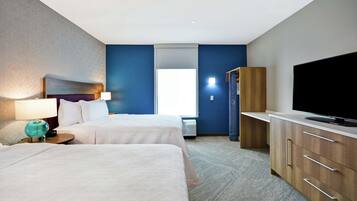 Ein Hotelzimmer mit zwei Betten, einem Fernseher, einem Kleiderschrank und einem Fenster mit Jalousien.