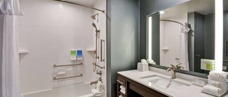 A modern bathroom with a bathtub, a vanity with a sink, and a large mirror.