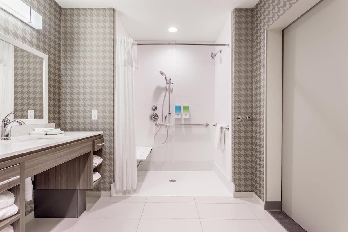 Un bany modern amb dutxa, un lavabo amb mirall i una barra de tovalloles.