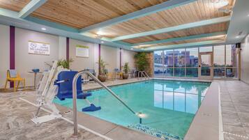 A pool area with a no diving sign, a lifeguard chair, and a view of the cityscape through large windows.