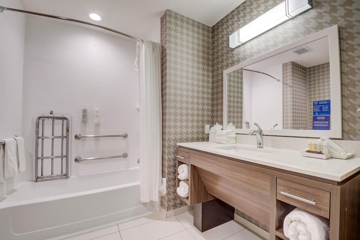 A modern bathroom with a walk-in shower, a vanity with a mirror, and a towel rack.