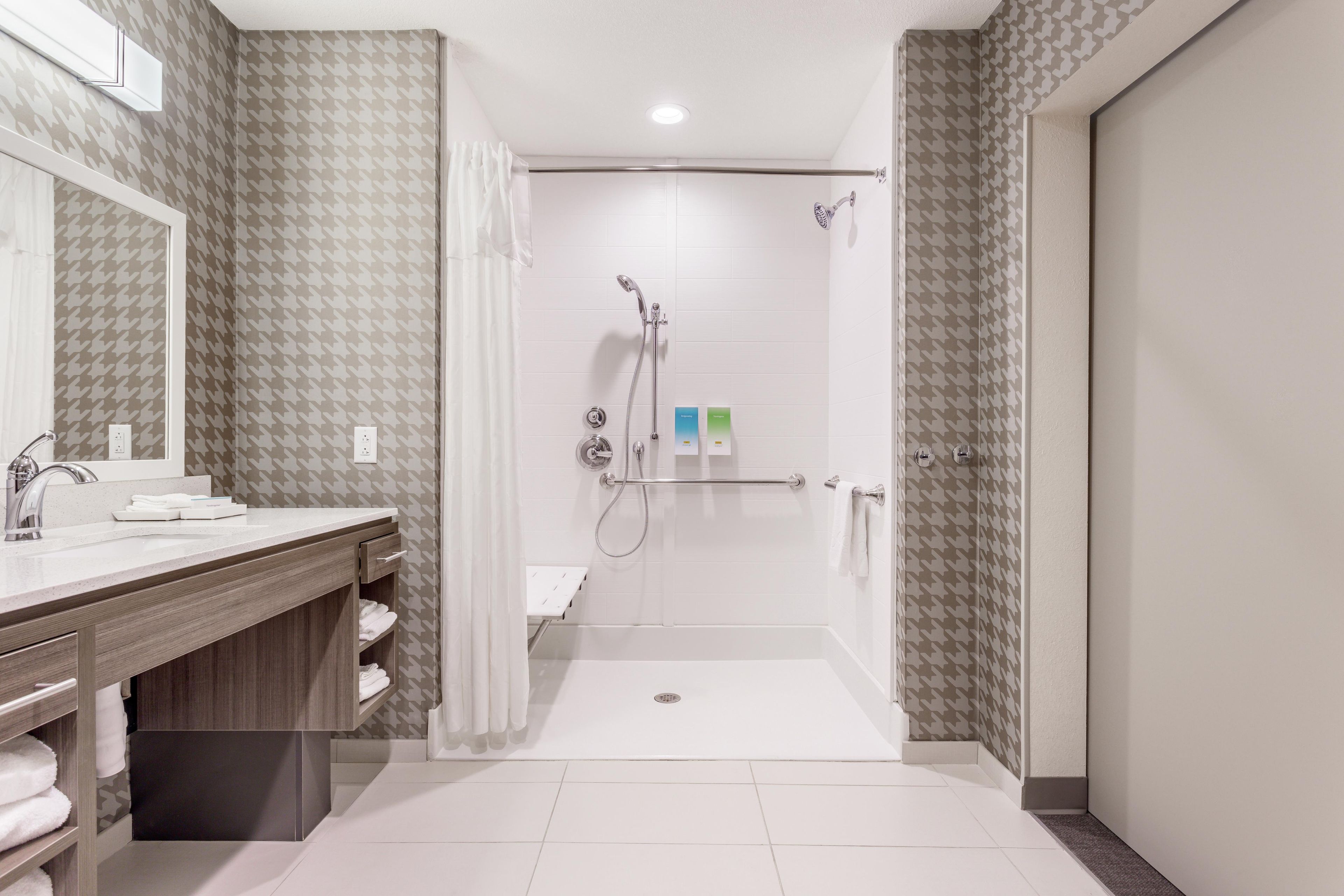 A modern bathroom with a shower, a vanity with a mirror, and a towel rack.