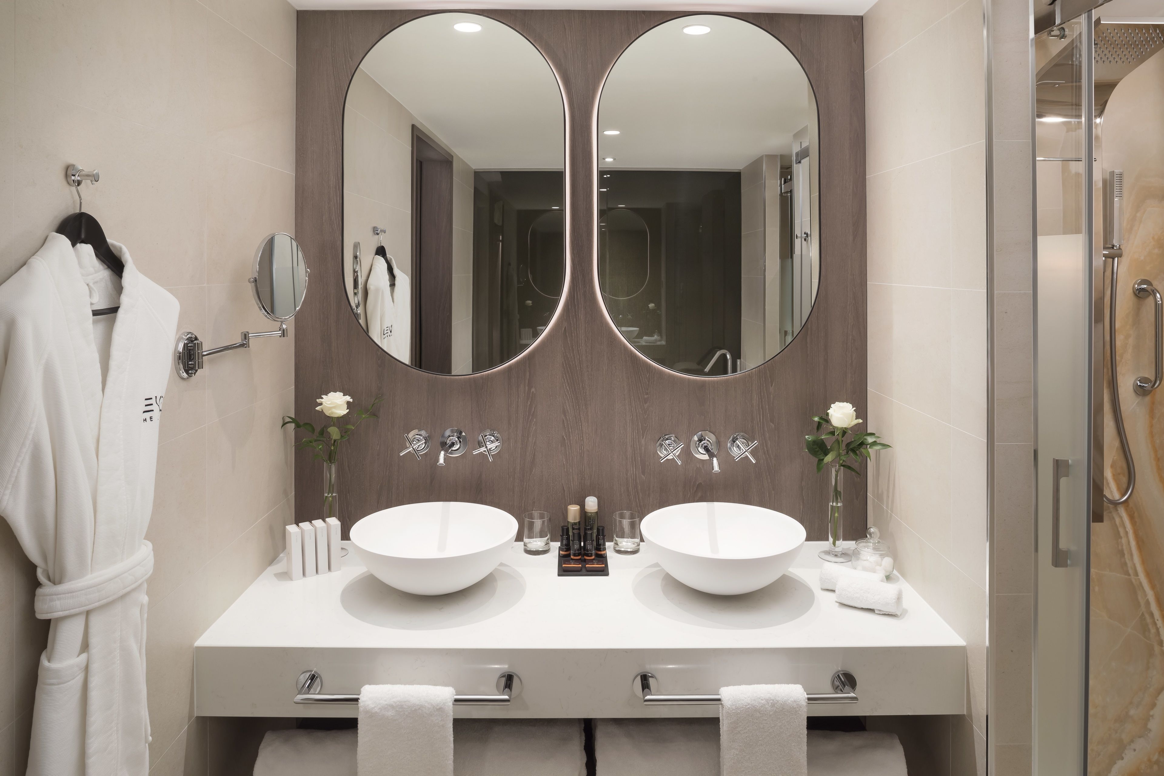 Un baño moderno con dos lavamanos, un espejo grande y una cabina de ducha de vidrio.