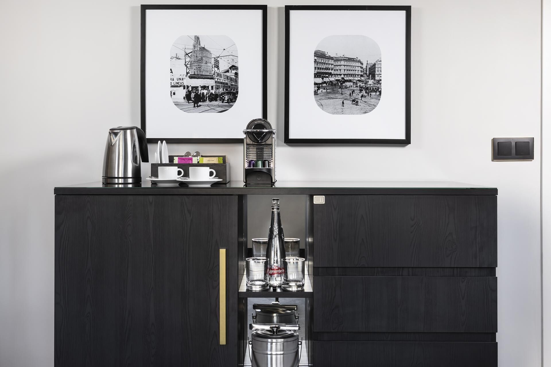 Una cocina moderna con un armario de madera oscura, una cafetera y dos fotografías en blanco y negro enmarcadas en la pared.
