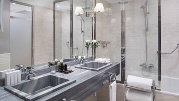 A modern bathroom with two sinks, a large mirror, and a glass-enclosed shower area.