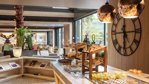 A breakfast buffet with various pastries and fruits, a wooden clock, and a modern interior with natural light. - The Level at Melia Castilla (Madrid)